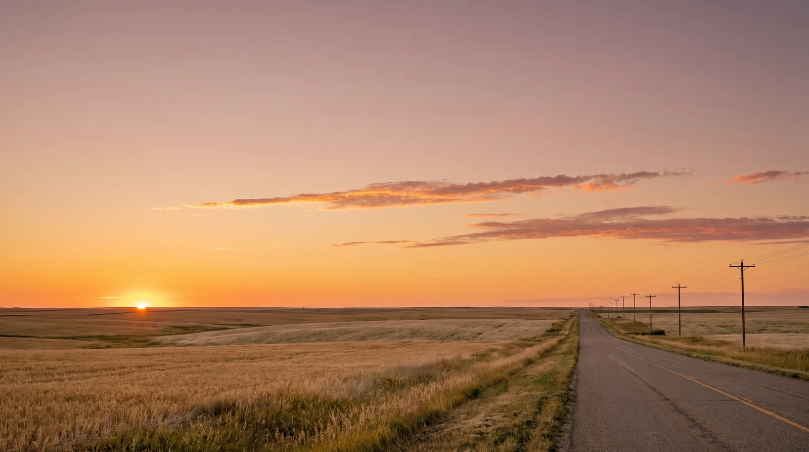 Prairie road at sunset under an amber sky